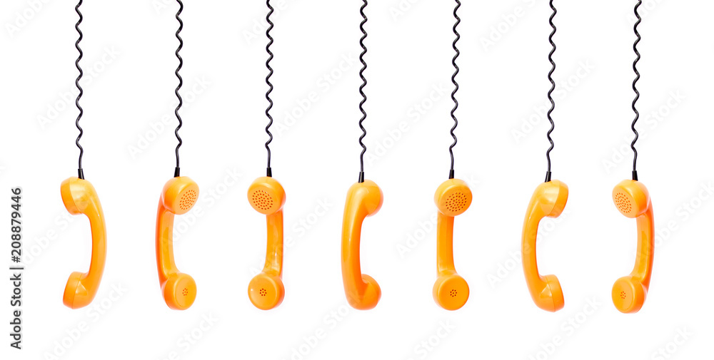 Handset piece from an old phone suspended by the phone cord, isolated on white background Handset piece from an old phone suspended by the phone cord, isolated on white background