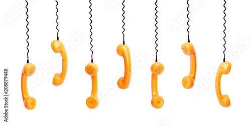 Handset piece from an old phone suspended by the phone cord, isolated on white background photo