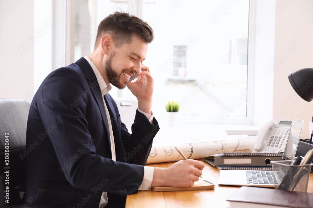 Businessman talking on phone while working in office Businessman talking on phone while working in office