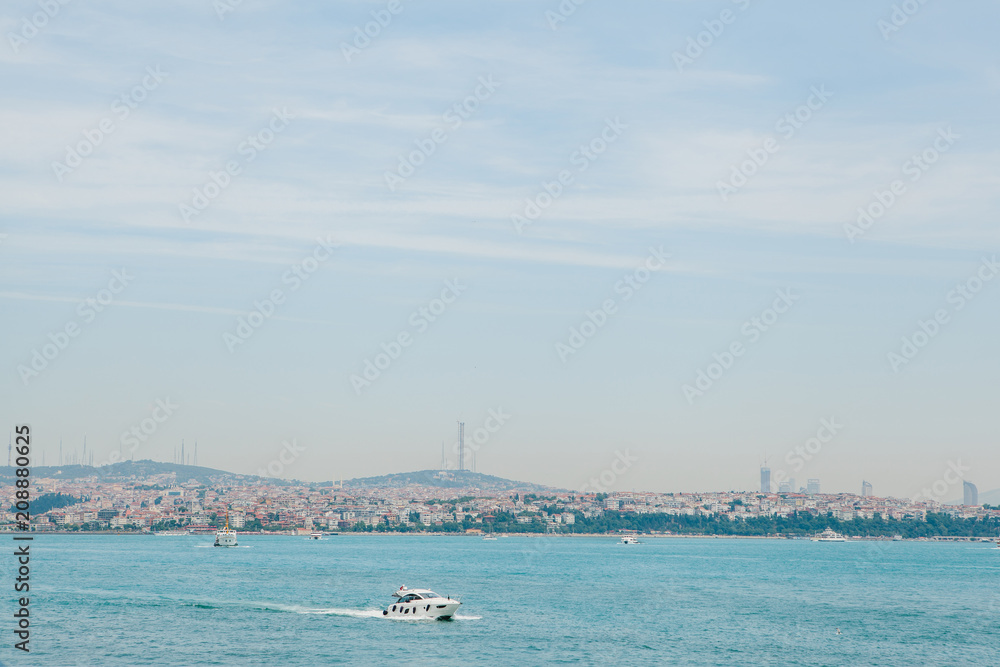 A speed boat sails along the Bosphorus in Istanbul. Urban architecture in the background