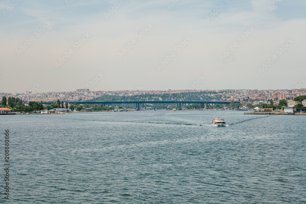 A speed boat sails along the Bosphorus in Istanbul. Urban architecture in the background