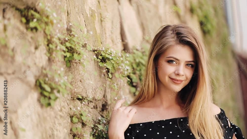Portrait of an attractive young woman standing on the street of a European city and looking into the camera. Natural beauty, female portrait, seductive look. Being self-confident concept