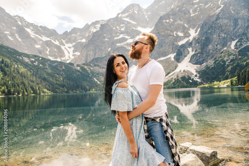 Young beautiful couple standing on a rock against the backdrop of a mountain lake in the Tatra National Park in Poland