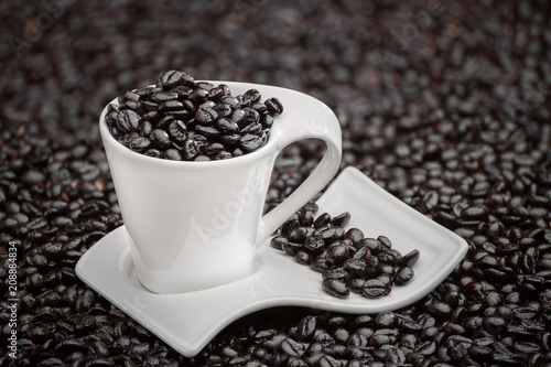 white cup of coffee with coffee beans on a textured sack background with lights and shadows