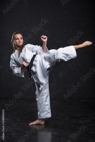  A girl in a white kimono with a black belt on a dark background