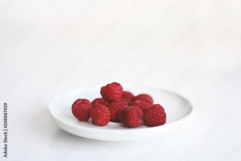 Himbeeren in einer weissen Schale vor weißem Hintergrund Himbeeren in einer weissen Schale vor weißem Hintergrund