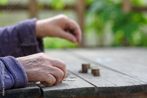 Money, coins, the grandmother on pension and the concept of life, minimum - hands of the old woman recalculate coins on a wooden table