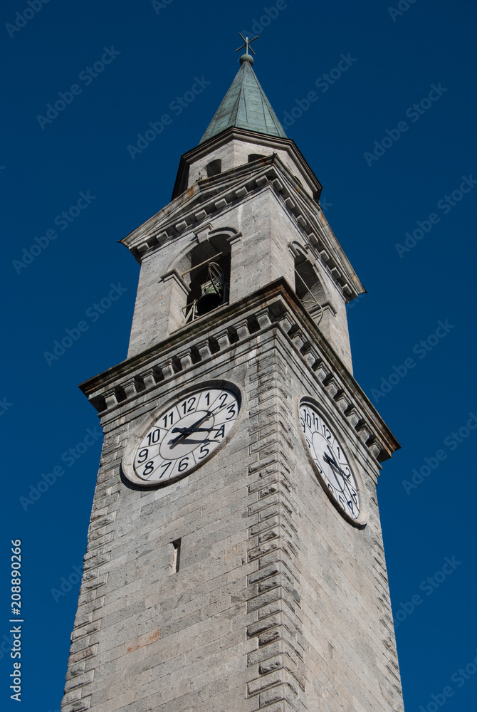 Light grey tower bell of the main church seen from below with blue sky in Pinzolo