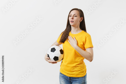 European woman, football fan in yellow uniform holding soccer ball, singing national country anthem isolated on white background. Sport, play football, cheer, fans people support, lifestyle concept. © ViDi Studio