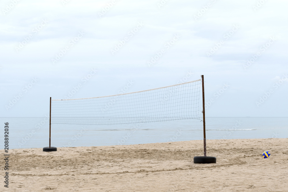Blue and Yellow volleyball in net and footprint on the sands