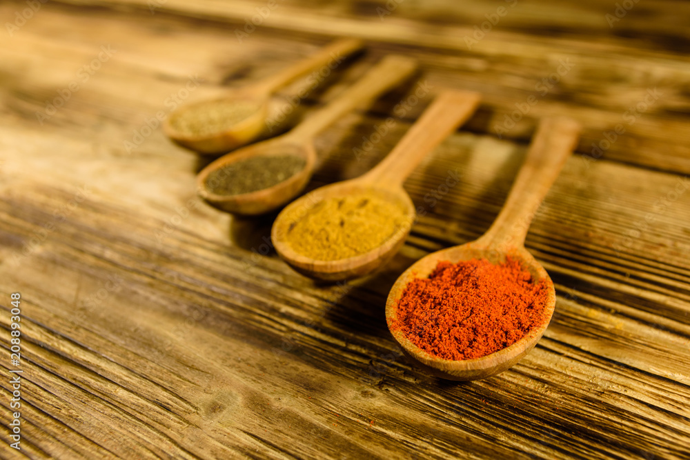 Spoons with the different spices on wooden table Spoons with the different spices on wooden table