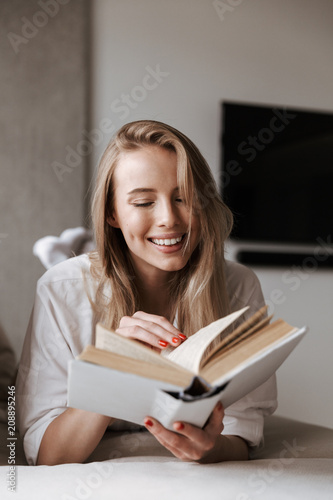 Happy young woman reading blank cover open book