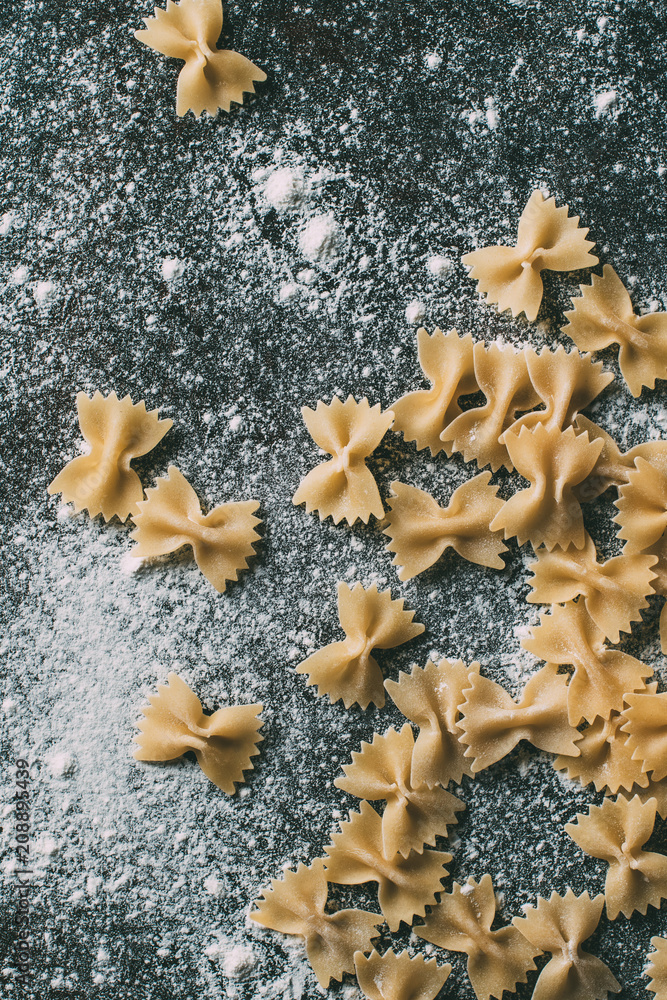 top view of raw farfalle pasta on table covered by flour