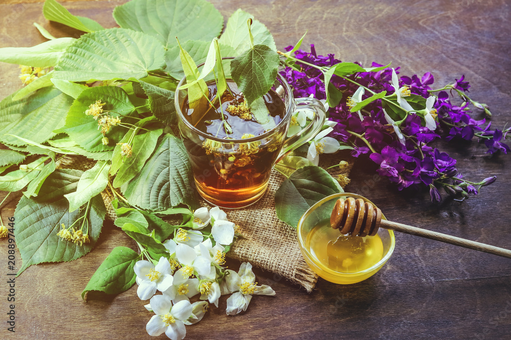 lime tea, lemon, flowers and honey in a glass bowl. on a wooden background. lime tea, lemon, flowers and honey in a glass bowl. on a wooden background.