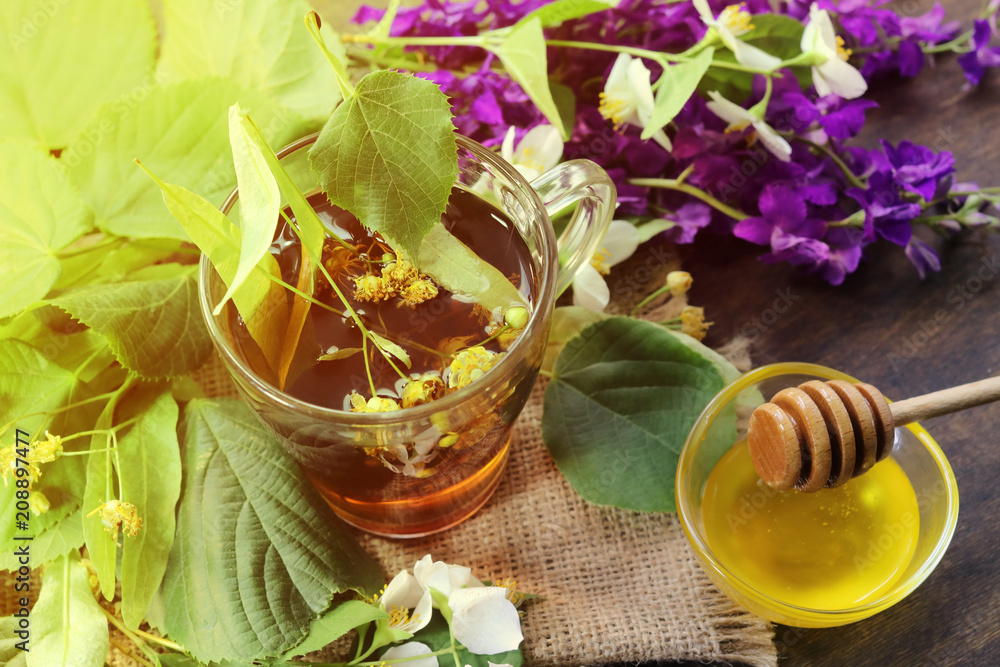 lime tea, lemon, flowers and honey in a glass bowl. on a wooden background. lime tea, lemon, flowers and honey in a glass bowl. on a wooden background.