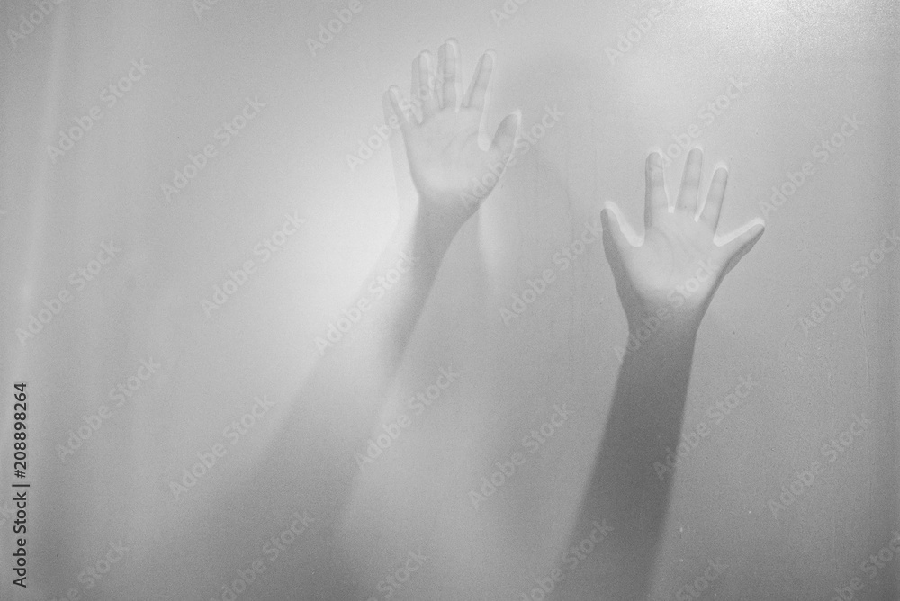 Shadow hands of the woman behind frosted glass.Blurry hand abstraction.Halloween background.Black and white picture. Shadow hands of the woman behind frosted glass.Blurry hand abstraction.Halloween background.Black and white picture.