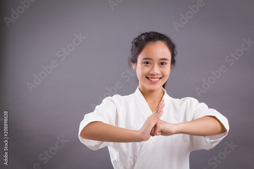 woman fighter portrait; asian woman practicing chinese martial arts, kungfu, taichi, taiji salutes you; girl self defense, hand combat martial arts training concept; 20s young adult asian woman model