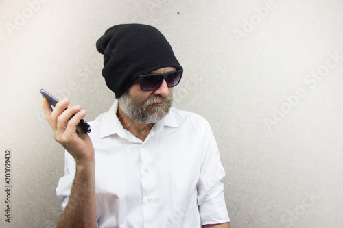 A man in a shirt with a beard wearing glasses and a hat talking on his cell phone © say_hope