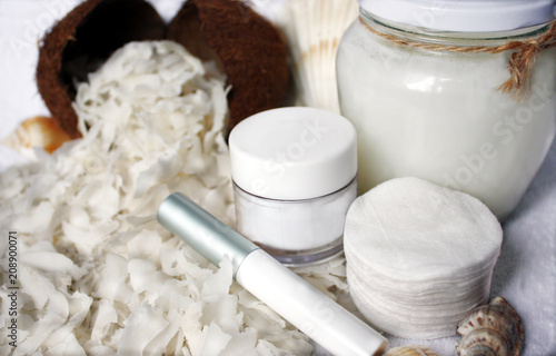 Sliced coconut pulp as an ingredient for coconut oil. A concept for facial and body care at home or procedures in the beauty spa. Cosmetic jars without logo: mocap, copy space.