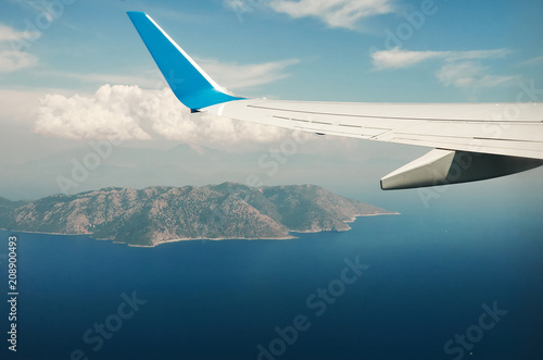 View from airplane window travel tourism. Wing of an airplane flying above the clouds over tropical island Turkey