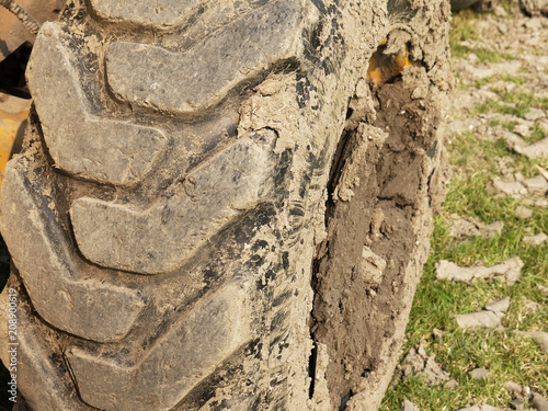 close up of tire bulldozer, yellow and covered with mud