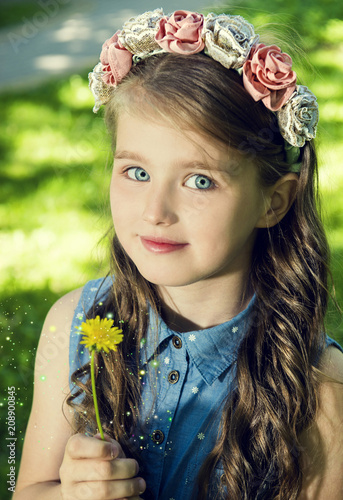Summer portrait of the blue-eyed girl with a dandelion