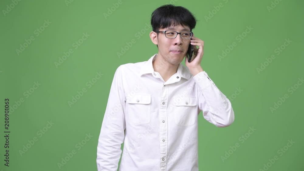 Happy young Asian businessman smiling while talking on the phone Happy young Asian businessman smiling while talking on the phone