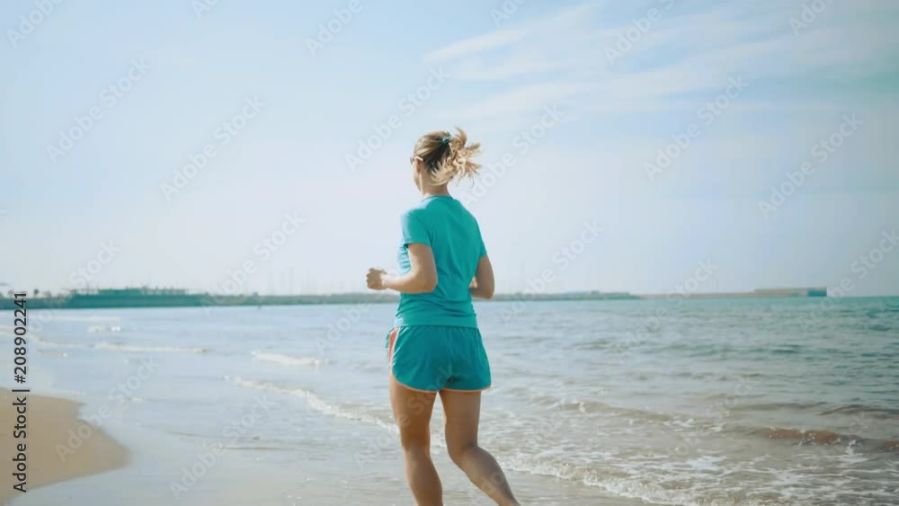 Running woman. Runner is jogging in sunny day light in the sea background. Female fitness training outdoors on summer day, 4K Running woman. Runner is jogging in sunny day light in the sea background. Female fitness training outdoors on summer day, 4K