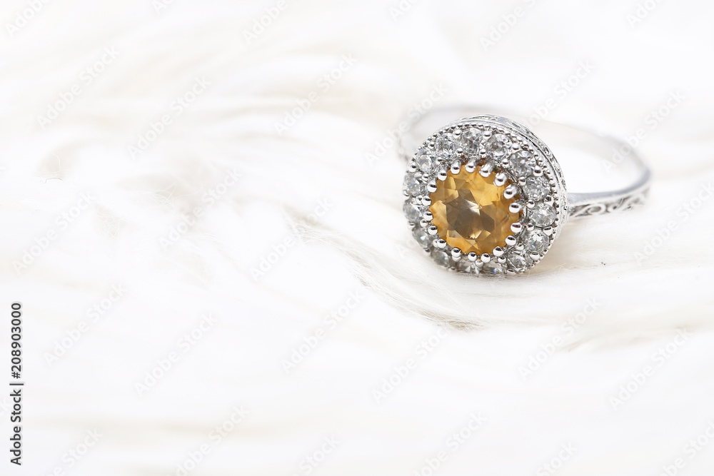 Yellow gem stone and diamond ring on white fabric Yellow gem stone and diamond ring on white fabric