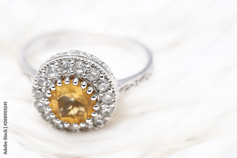 Yellow gem stone and diamond ring on white fabric Yellow gem stone and diamond ring on white fabric