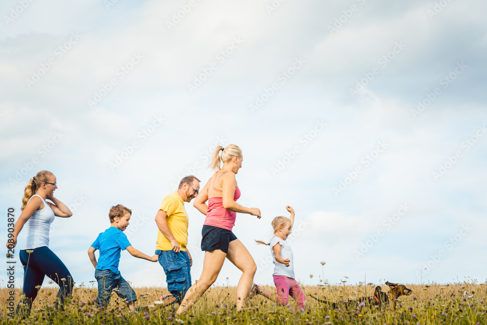 Family running for better fitness in summer jogging over a field
