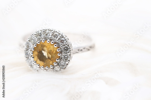 Yellow gem stone and diamond ring on white fabric