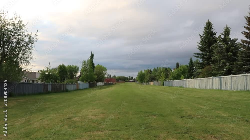A shot of a small grass field separating residential housing and leading to the main road.
The field have no sidewalk and accessible to the public A shot of a small grass field separating residential housing and leading to the main road.
The field have no sidewalk and accessible to the public