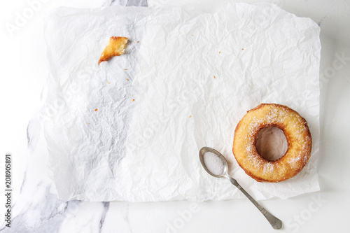 Last homemade puff pastry deep fried donut or cronut with sugar on crumpled paper over white marble texture background. Flat lay, space. photo