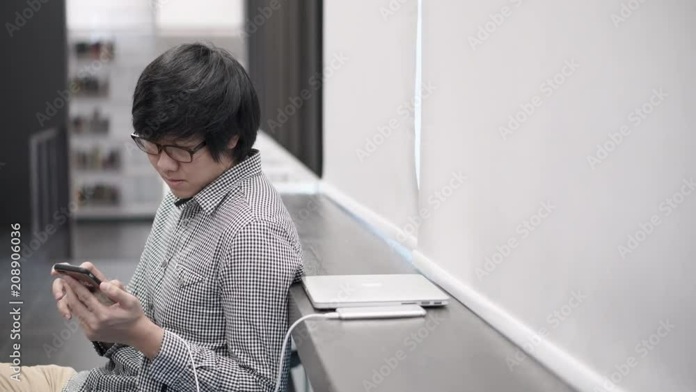 Young Asian business man using smartphone on social media application and playing game at break time in office. Urban lifestyle in working space concept. 4K video Young Asian business man using smartphone on social media application and playing game at break time in office. Urban lifestyle in working space concept. 4K video