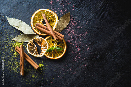 Dry lemons and spices on black wooden background