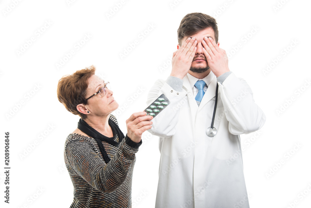 Male doctor covering eyes and female patient showing pills Male doctor covering eyes and female patient showing pills