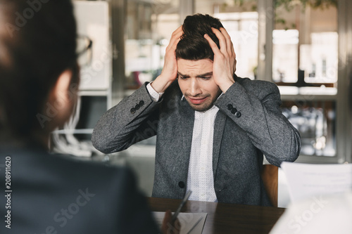 Fényképezés Shocked upset man 30s worrying and grabbing his head during job interview in off
