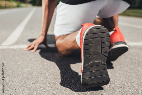 close up view of running shoes of male sprinter in starting position on running track