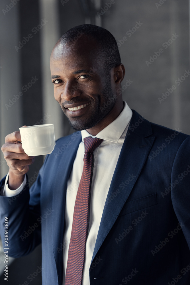 happy young businessman with cup of coffee looking at camera happy young businessman with cup of coffee looking at camera