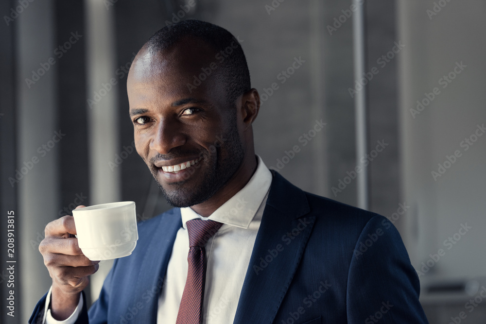 smiling young businessman with cup of coffee looking at camera smiling young businessman with cup of coffee looking at camera