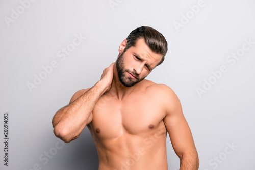 Portrait of handsome sad exhausted tired unhappy shirtless topless upset bearded athlete having pain in neck touching with hand isolated on gray background copy-space