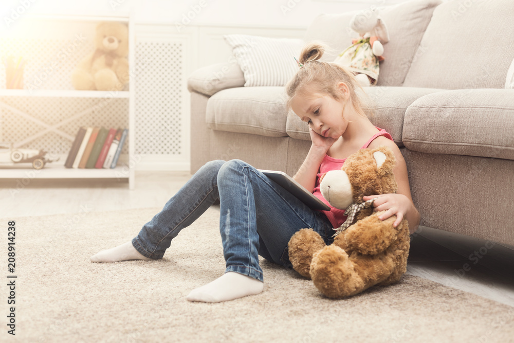 Little girl with tablet sitting on floor at home Little girl with tablet sitting on floor at home