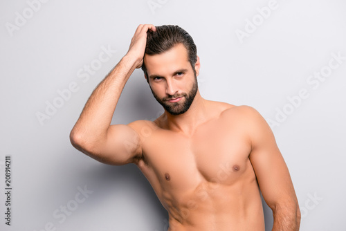 Portrait of handsome sexy tempting cool brutal masculine confident bearded athlete touching his perfect ideal with wax gel haircut isolated on gray background copyspace