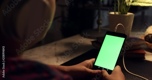 Over the shoulder view of asian boy using tablet computer with headphone, Green screen of technology being used. Chroma Key tablet.