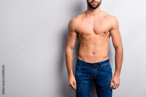 Cropped close up photo of handsome attractive ideal perfect stunning strong muscular flawless man's body with six-pack wearing dark blue denim jeans isolated on gray background copy-space