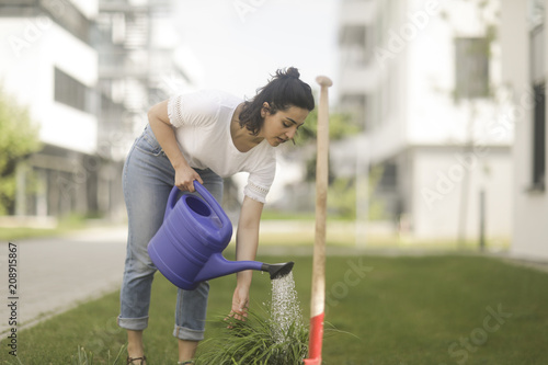 Woman standing in garden watering a plant