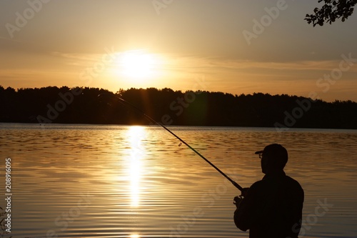 Silhouette of fisherman catching the fish during sunrise