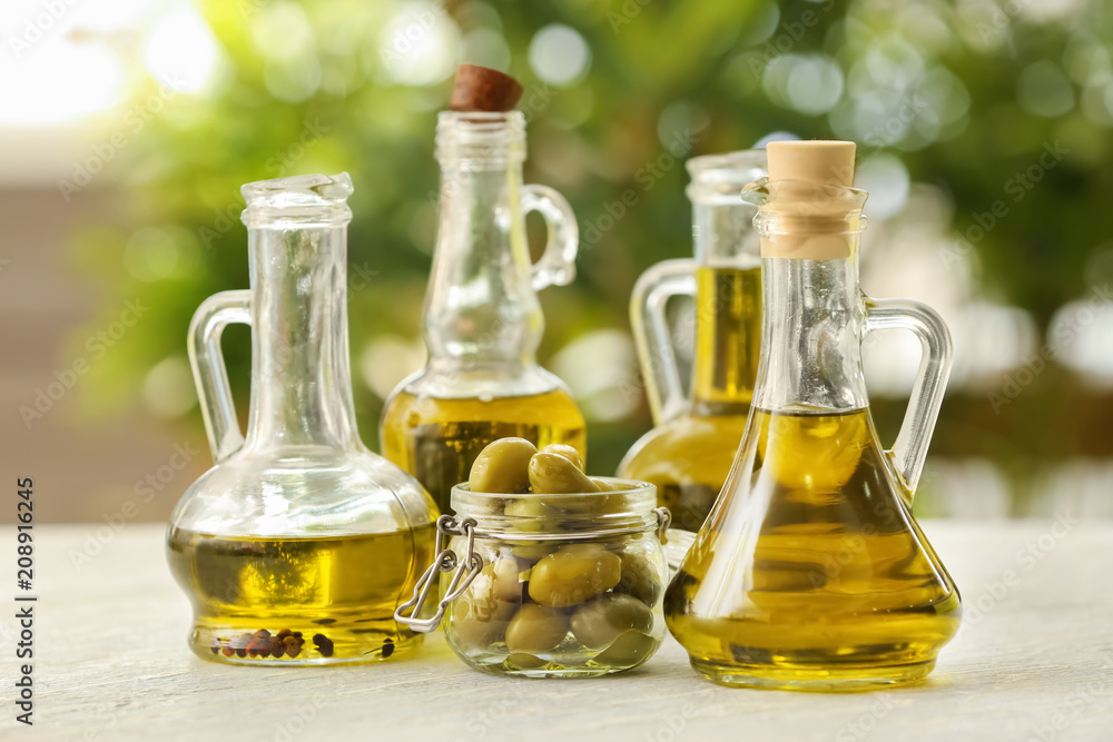 Jugs with olive oil on table against blurred background Jugs with olive oil on table against blurred background