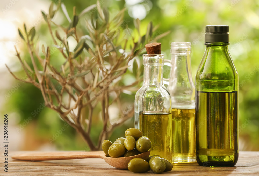 Bottles with olive oil on table against blurred background Bottles with olive oil on table against blurred background